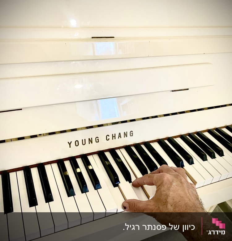 יד מכוונת פסנתר על קלידים לבנים ושחורים